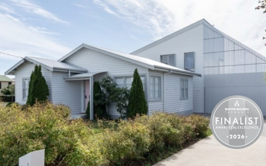Modern light grey house with angular rooflines, shrubs in front, and a silver badge reading: Finalist, Master Builders Tasmania Awards for Excellence 2026.